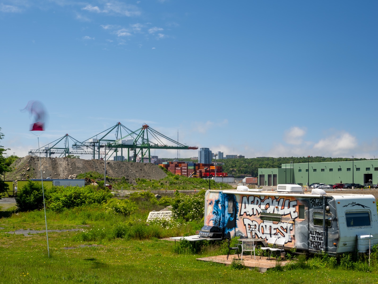Africville, protest caravan with industry behind.