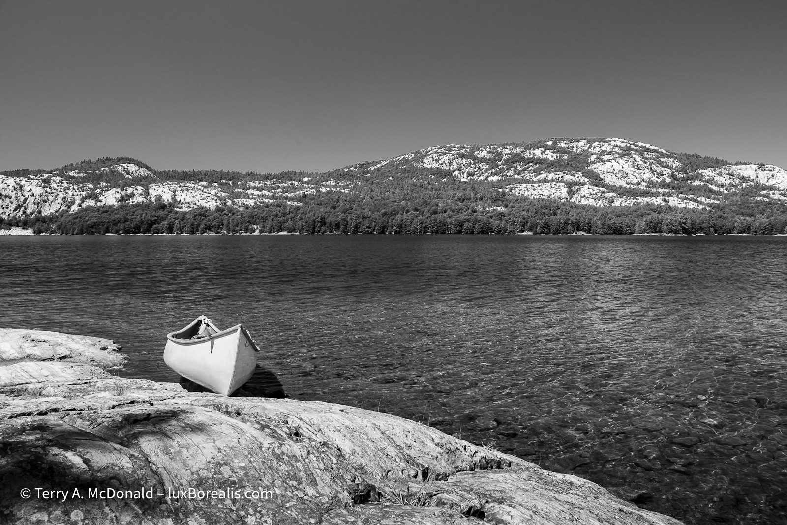 OSA Lake and Killarney Range
A single canoe is on the rocky shore in the foreground with OSA Lake and the Killarney Range of white quartzite hills. ©Terry A. McDonald – luxBorealis.com